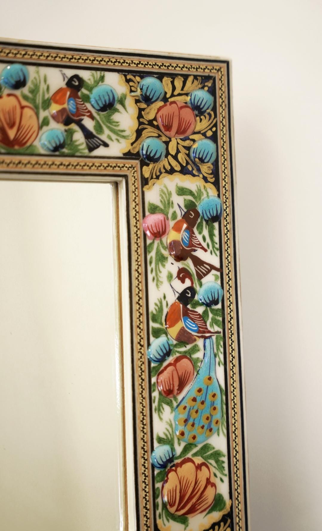 hand-painted relief enamel mirror detail with birds and colorful floral motifs in blue and orange.