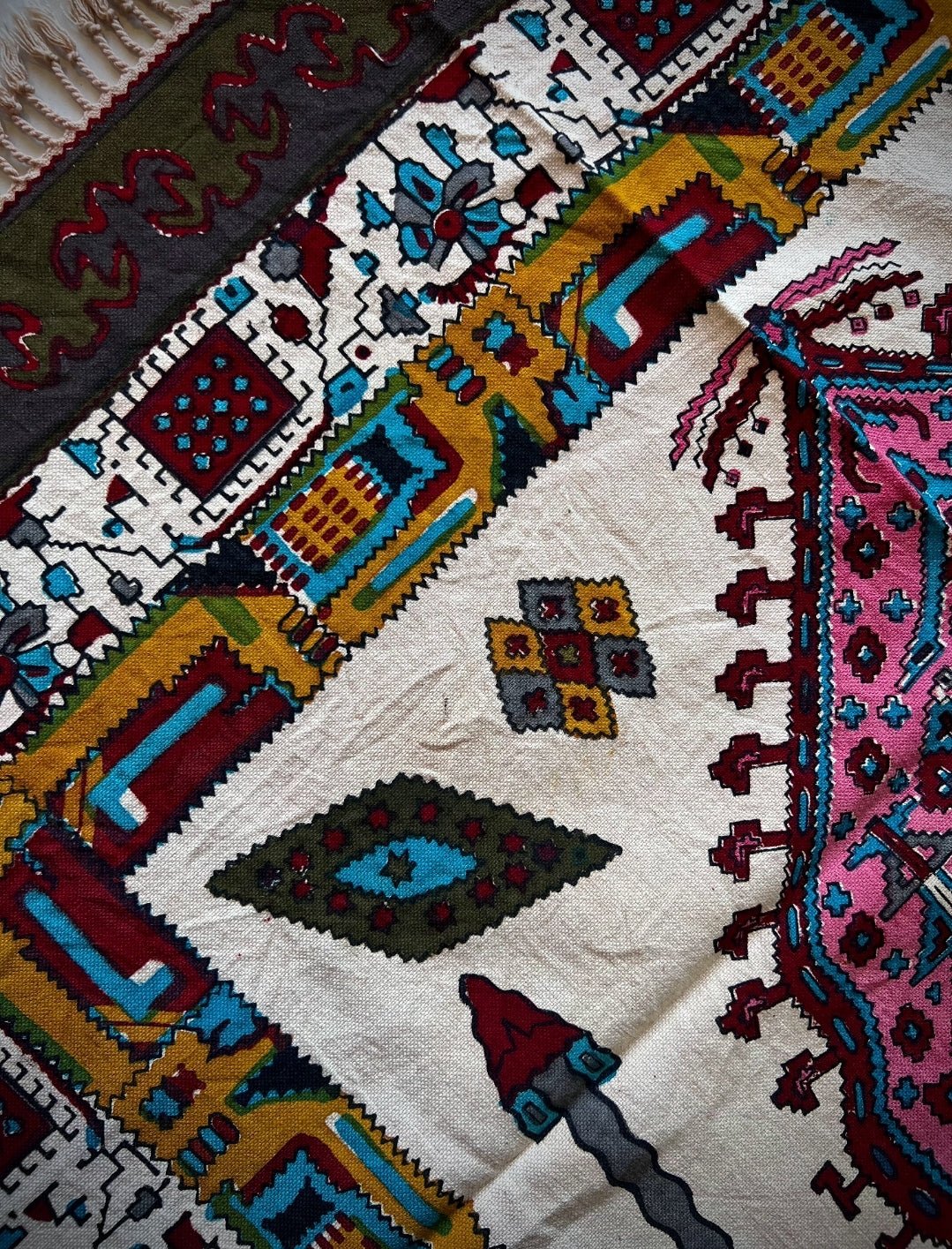 Block printed cotton textile featuring vibrant patterns in pink, terracotta, and geometric motifs.