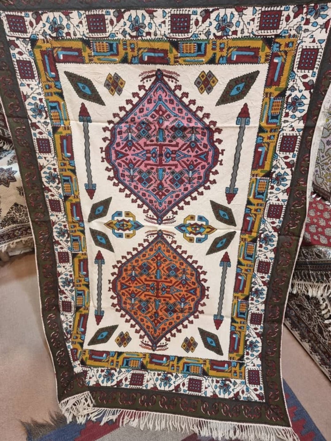 Block printed cotton textile featuring vibrant geometric patterns in pink, terracotta, and blue.