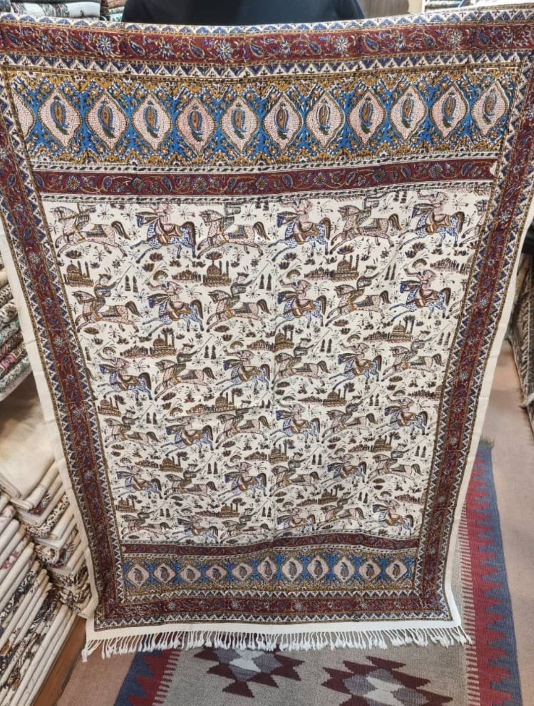 Block printed cotton textile featuring dynamic horse-rider scenes and paisley borders, size 100x150 cm.