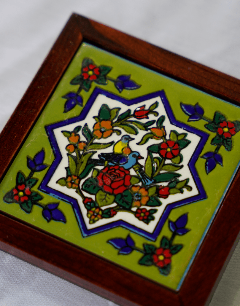 hand-painted ceramic coaster featuring a persian bird and floral motif, framed in polished wood.