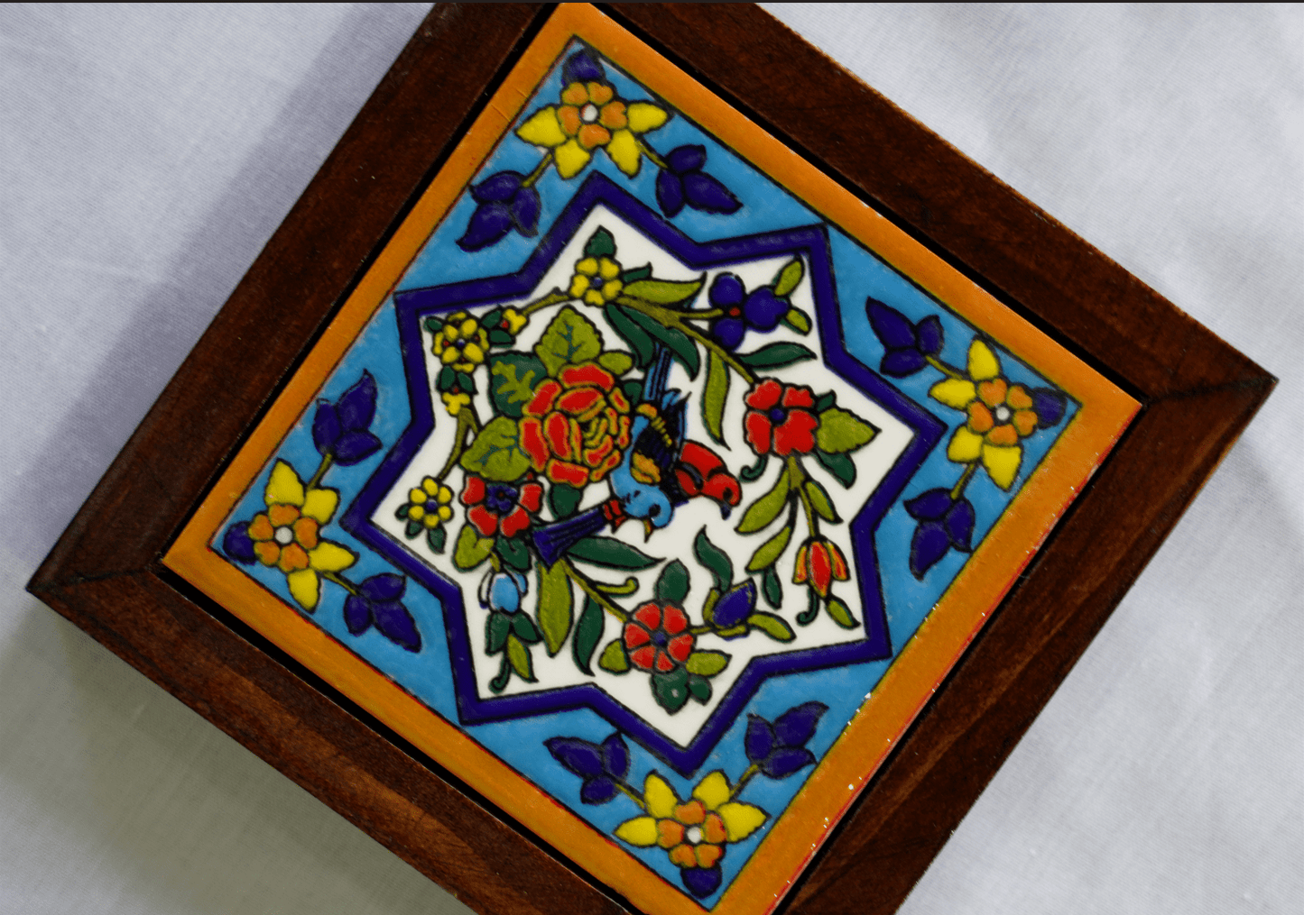 hand-painted ceramic coaster – bird & floral motif with vibrant persian design on a polished wooden base.