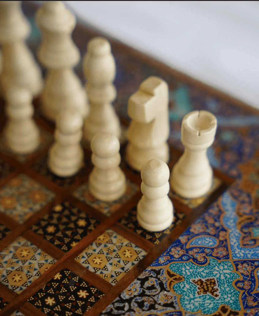compact chess and backgammon set with handcrafted wooden pieces on a decorative patterned board.