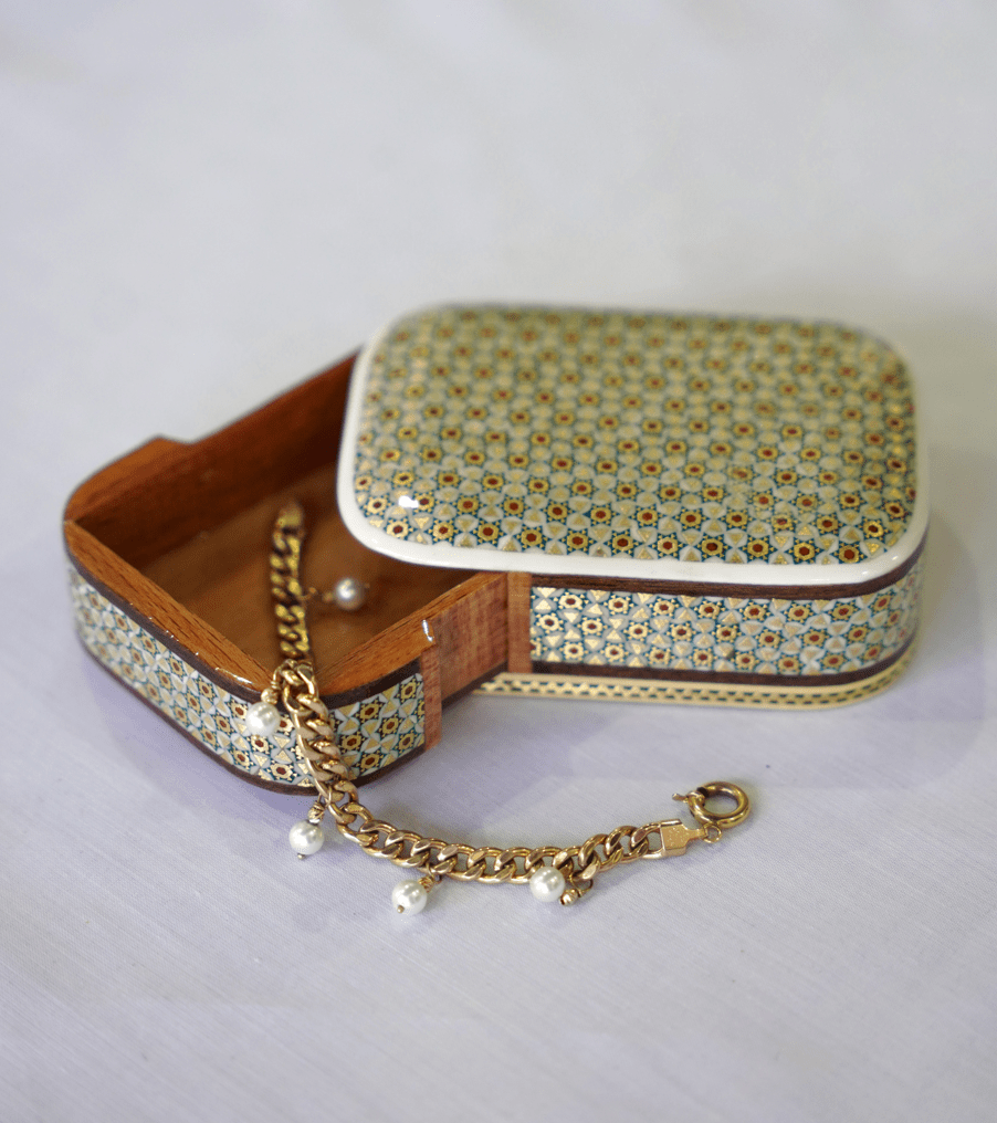 Handmade wooden keepsake box opened with a gold chain bracelet inside and intricate marquetry design.