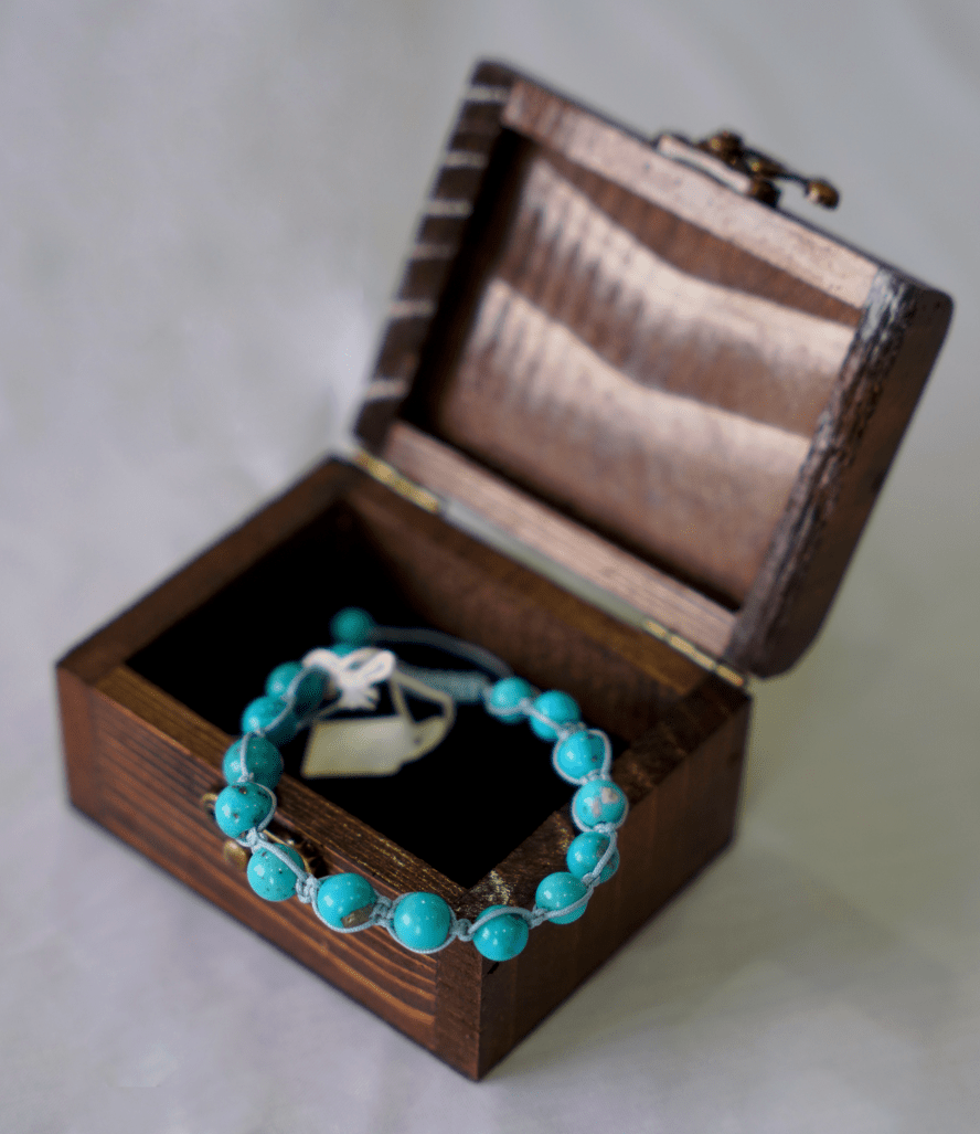 turquoise hand-braided gemstone bracelet displayed in a wooden box, showcasing its natural turquoise stones.