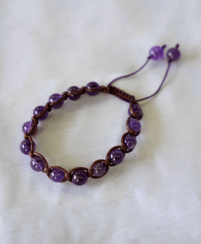 Amethyst macrame bracelet featuring hand-braided natural gemstone beads in translucent violet tones.