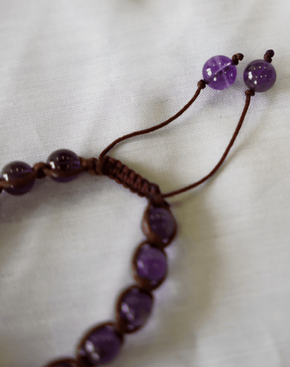 Close-up of an amethyst macrame bracelet showing hand-braided natural gemstone beads and adjustable ties.
