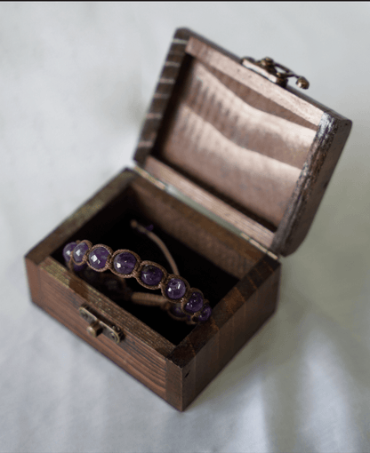 Amethyst macrame bracelet displayed inside a wooden box with elegant violet gemstones.