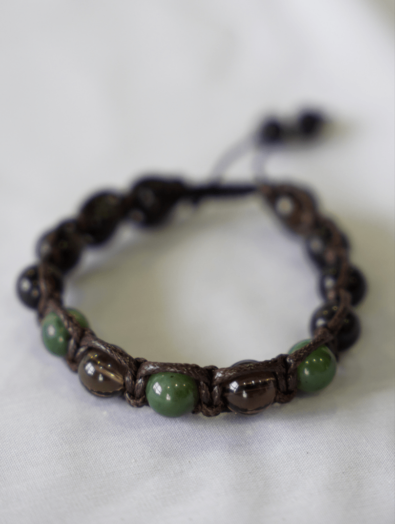 macrame gemstone bracelet showcasing smoky quartz, jade and obsidian on a textured background.
