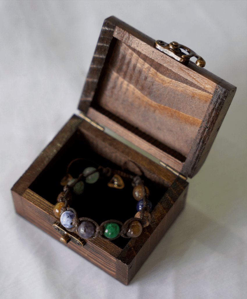 collector’s edition multi-stone macramé bracelet showcased in an open wooden box.