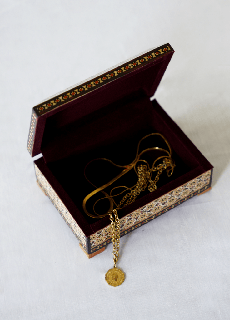 handmade wooden jewelry box open, displaying a delicate gold necklace inside.