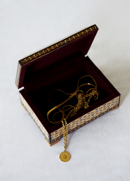 Handmade wooden jewelry box open, displaying a delicate gold necklace inside.