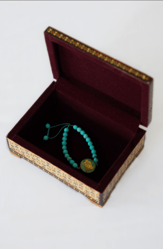 Handmade wooden jewelry box open, showcasing a turquoise bracelet inside, crafted with traditional techniques.